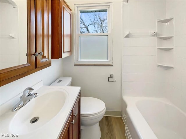 bathroom with baseboards, toilet, wood finished floors, and vanity