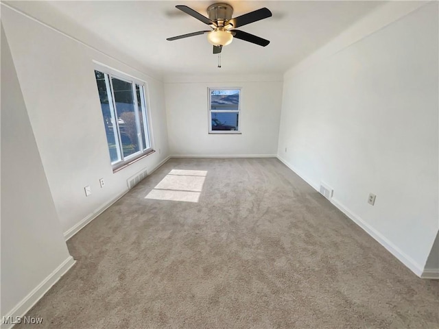 carpeted spare room featuring visible vents, baseboards, and a ceiling fan