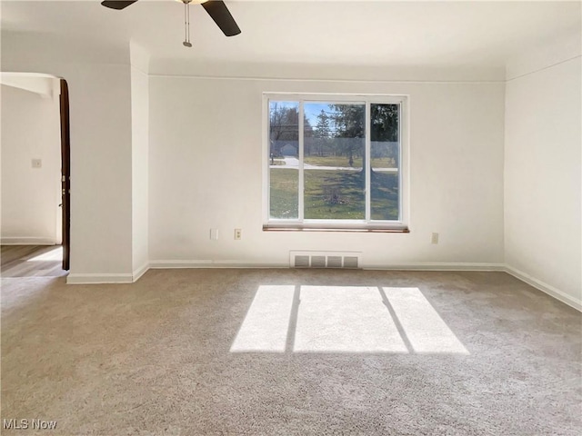 unfurnished room with baseboards, visible vents, arched walkways, ceiling fan, and carpet flooring