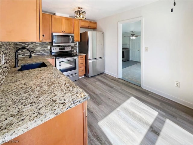 kitchen featuring backsplash, ceiling fan, washer / dryer, stainless steel appliances, and a sink