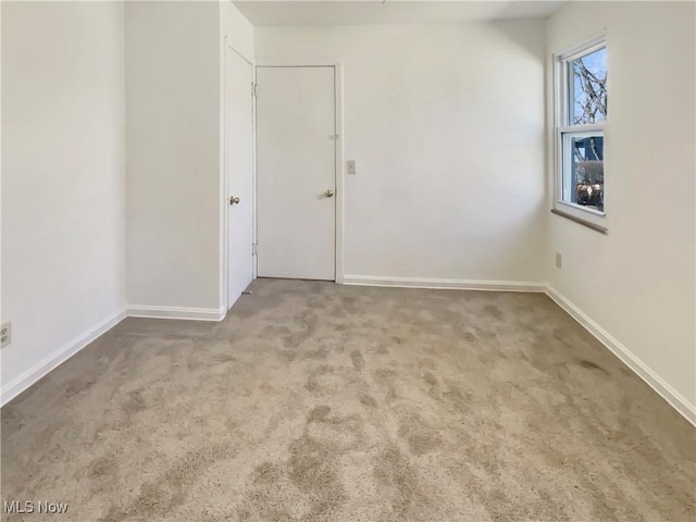 carpeted empty room featuring baseboards