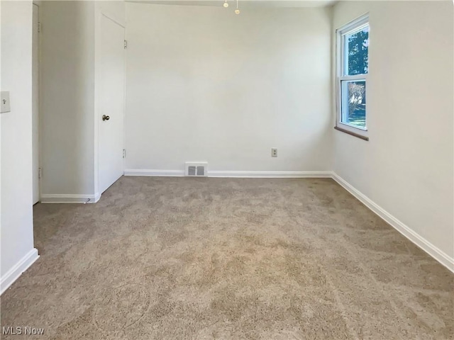 carpeted empty room featuring visible vents and baseboards