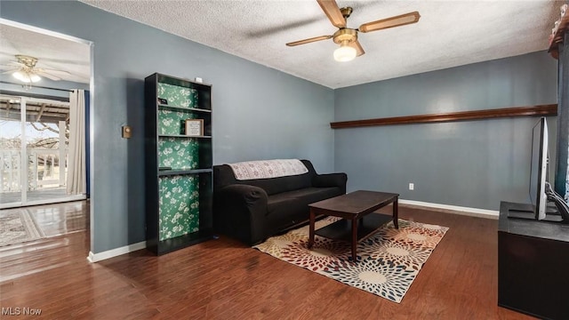 living area featuring baseboards, a textured ceiling, a ceiling fan, and wood finished floors