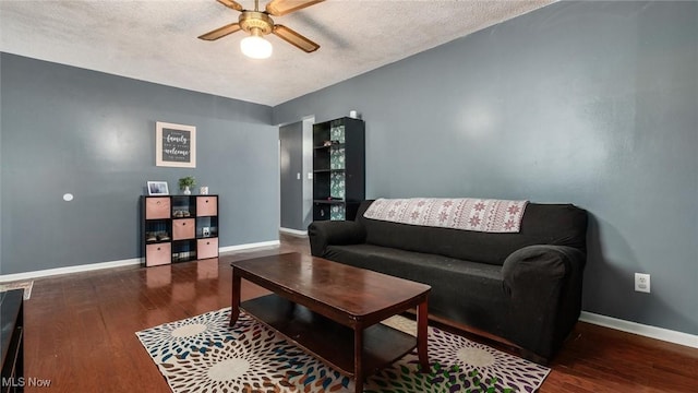 living area featuring a textured ceiling, wood finished floors, baseboards, and ceiling fan