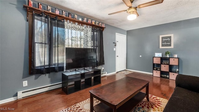 living area with baseboards, ceiling fan, baseboard heating, wood finished floors, and a textured ceiling