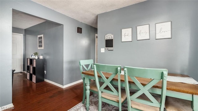 dining room with wood finished floors, baseboards, and a textured ceiling