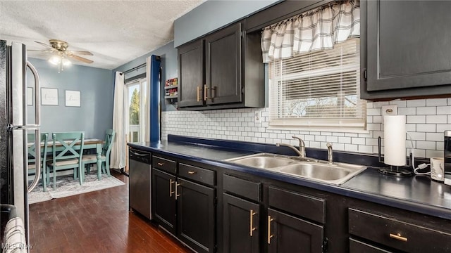 kitchen featuring dark countertops, dark wood-style floors, stainless steel appliances, a ceiling fan, and a sink