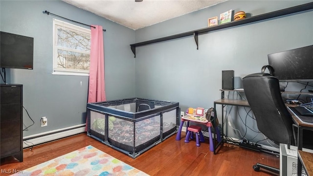 bedroom featuring a baseboard heating unit, baseboards, and wood finished floors