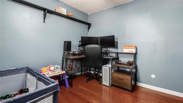 home office with a textured ceiling, baseboards, and wood finished floors