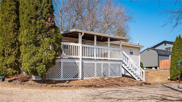 rear view of property with an outdoor structure, stairs, and a shed