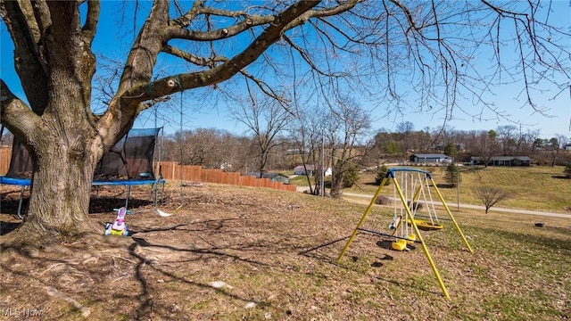 view of yard featuring a playground, a trampoline, and fence