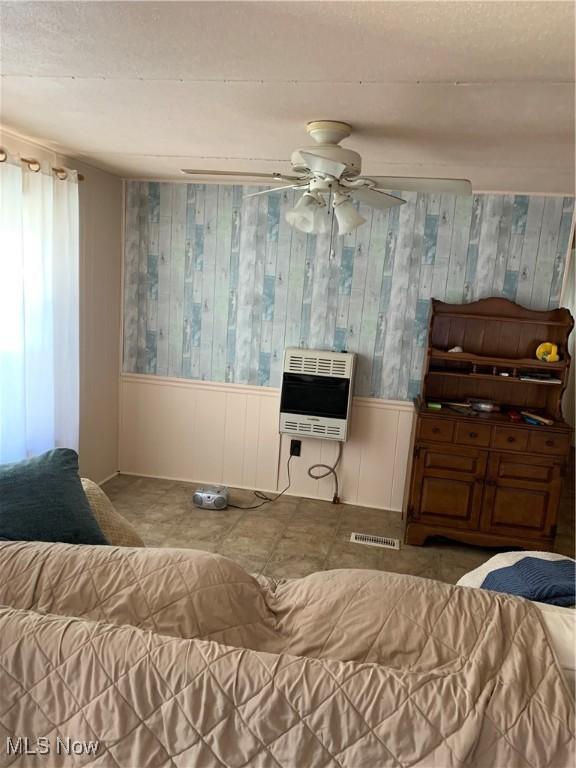 living room featuring heating unit, visible vents, and ceiling fan