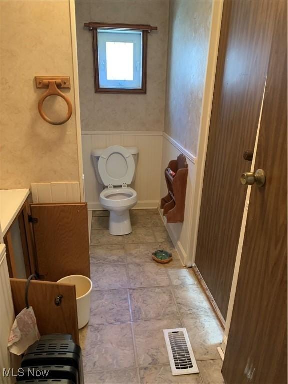 bathroom with tile patterned floors, visible vents, a wainscoted wall, toilet, and vanity