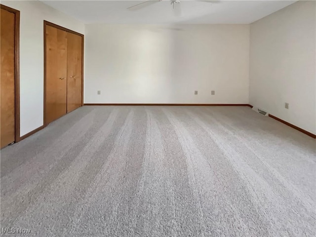 unfurnished bedroom with visible vents, light colored carpet, baseboards, and multiple closets