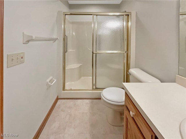 bathroom with toilet, a stall shower, vanity, and baseboards