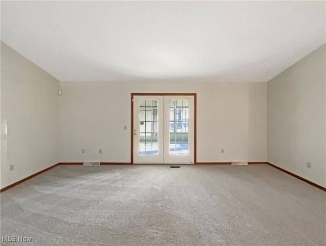 carpeted empty room featuring lofted ceiling, baseboards, and visible vents