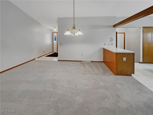 unfurnished living room featuring a notable chandelier, light colored carpet, visible vents, and baseboards