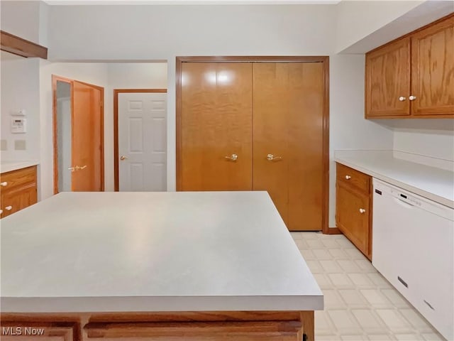 kitchen featuring dishwasher, brown cabinetry, light floors, and light countertops