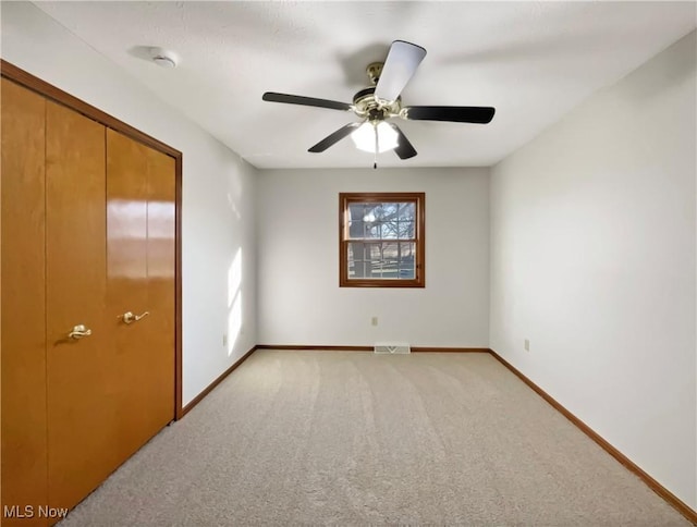 unfurnished bedroom with light colored carpet, baseboards, visible vents, and ceiling fan