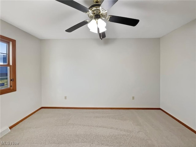 carpeted empty room featuring baseboards and ceiling fan