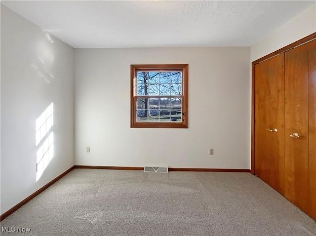 unfurnished bedroom featuring carpet flooring, multiple windows, baseboards, and visible vents