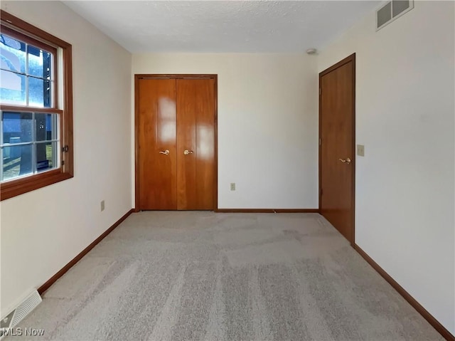 unfurnished bedroom with visible vents, baseboards, and light carpet