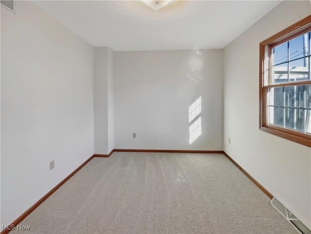 carpeted spare room featuring visible vents and baseboards