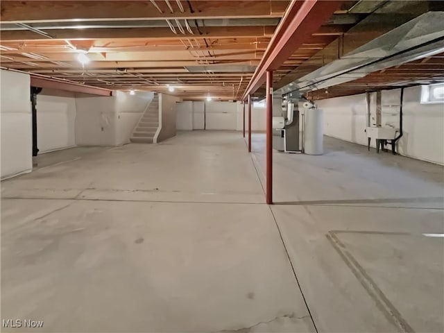 unfinished below grade area featuring heating unit, stairway, gas water heater, and a sink