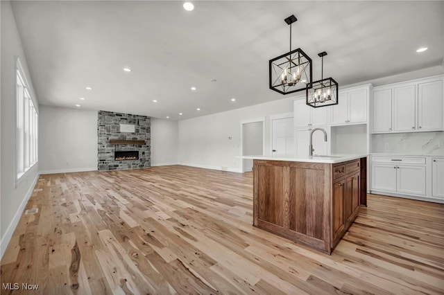 kitchen featuring an inviting chandelier, a sink, light countertops, white cabinets, and light wood-type flooring