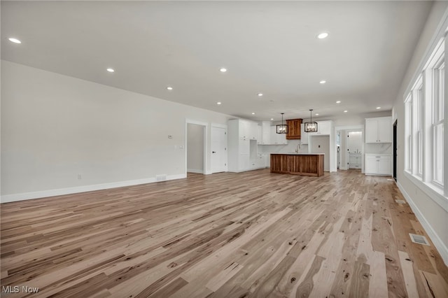 unfurnished living room with light wood finished floors, visible vents, recessed lighting, and baseboards