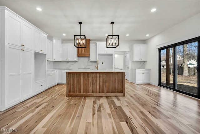 kitchen with light wood finished floors, tasteful backsplash, a chandelier, recessed lighting, and white cabinets