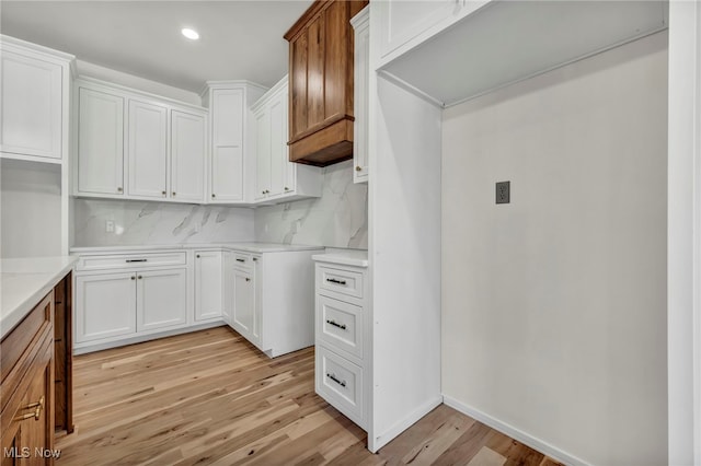 kitchen with light wood-type flooring, tasteful backsplash, white cabinetry, recessed lighting, and light countertops