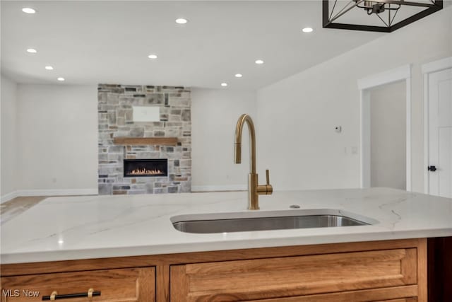 kitchen with brown cabinetry, open floor plan, light stone countertops, and a sink