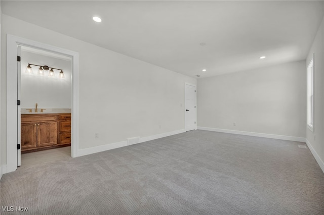 unfurnished room with recessed lighting, light colored carpet, baseboards, and a sink