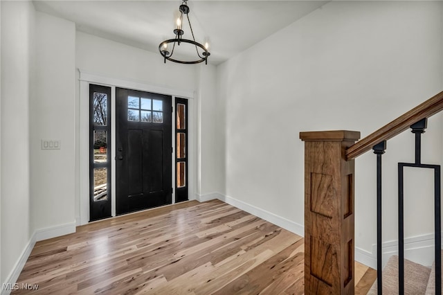 entryway featuring an inviting chandelier, baseboards, and light wood-type flooring