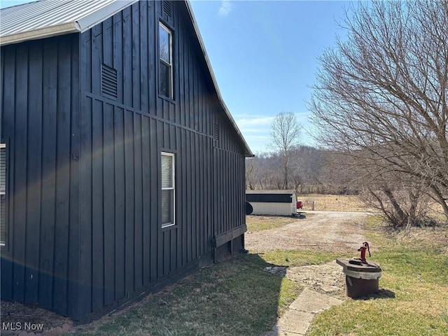 view of side of home with an outbuilding, a lawn, board and batten siding, and an outdoor fire pit