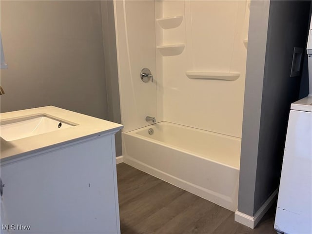 full bath featuring vanity, shower / tub combination, wood finished floors, and baseboards