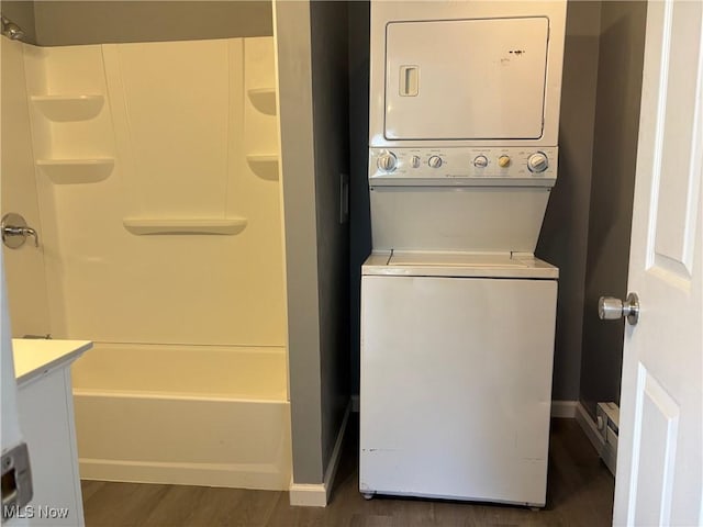 washroom with dark wood finished floors, laundry area, baseboards, and stacked washer and clothes dryer