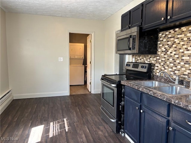 kitchen featuring stacked washer and dryer, a sink, dark wood-style floors, appliances with stainless steel finishes, and decorative backsplash