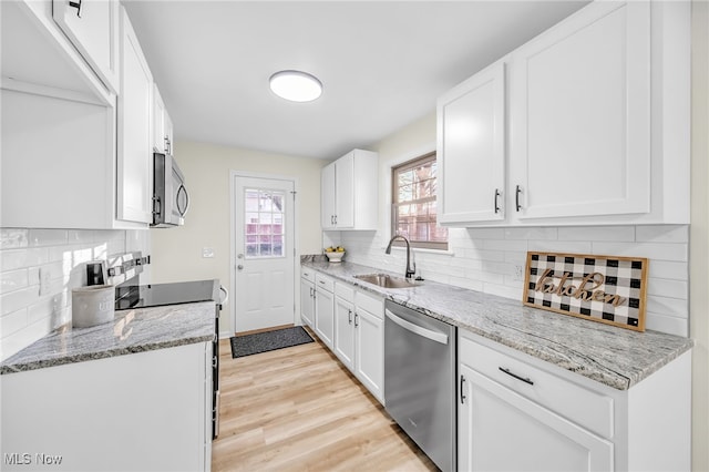 kitchen with a sink, stainless steel appliances, light wood-style floors, and white cabinetry