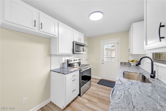 kitchen with light stone counters, stainless steel appliances, light wood-style floors, and a sink