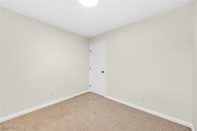 empty room featuring light colored carpet and baseboards