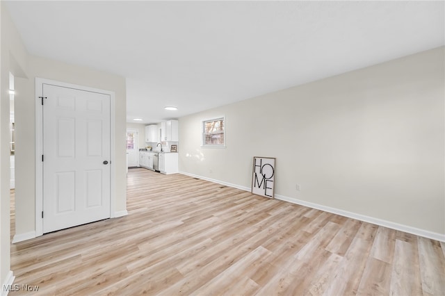 unfurnished room with baseboards, light wood-style floors, and a sink