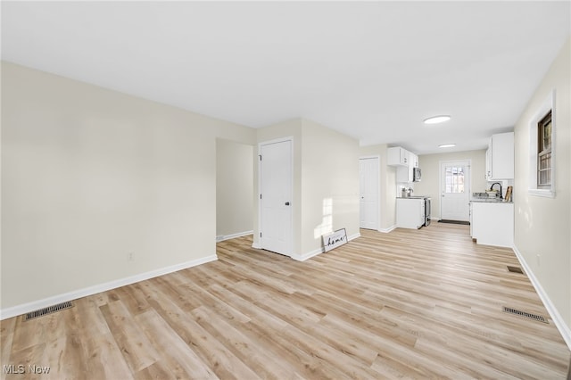 unfurnished living room with visible vents, baseboards, and light wood-style flooring