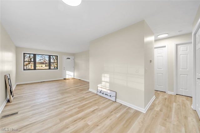 empty room with visible vents, light wood-style flooring, and baseboards