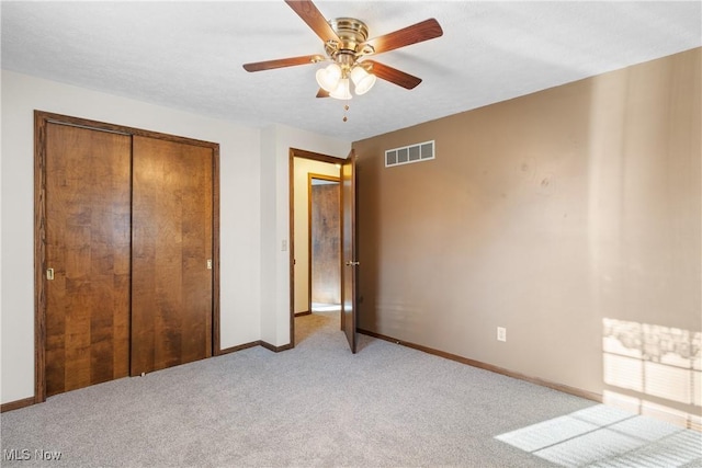 unfurnished bedroom with visible vents, baseboards, light colored carpet, a closet, and a ceiling fan