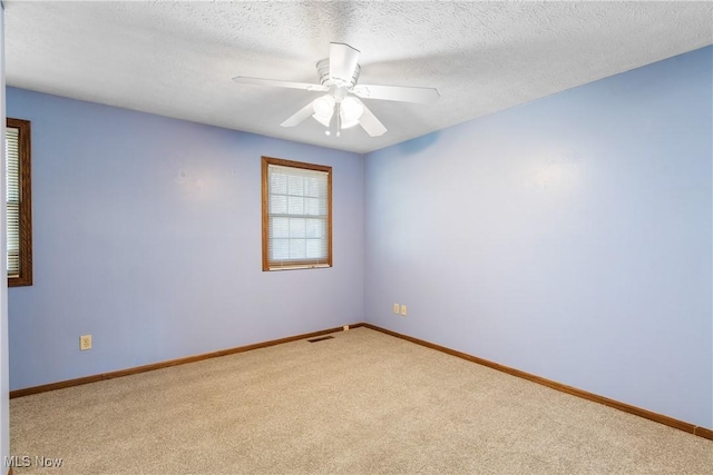 spare room featuring a textured ceiling, baseboards, carpet floors, and ceiling fan