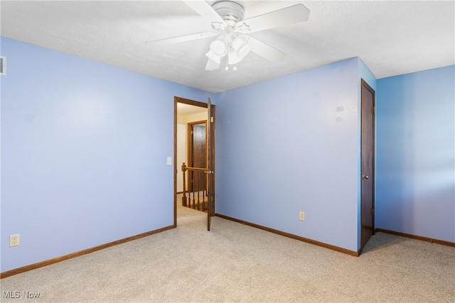 unfurnished bedroom with light colored carpet, a textured ceiling, and baseboards