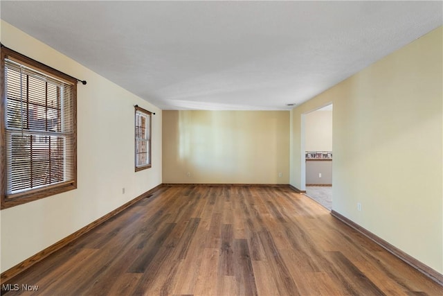 spare room with wood finished floors, baseboards, and a wealth of natural light