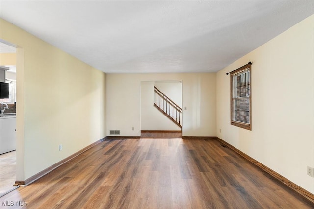 spare room with stairs, visible vents, wood finished floors, and baseboards